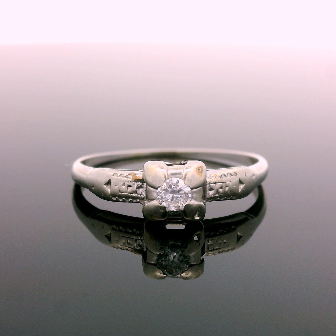 Antique Art Deco 14K White Gold Diamond Ring with Engraved Shoulders: Antique Art Deco 14K White Gold Diamond Ring with Engraved Shoulders Discover the elegance of this Antique Art Deco ring crafted in 14K white gold. Featuring a petite .08 carat diamond with a stunning