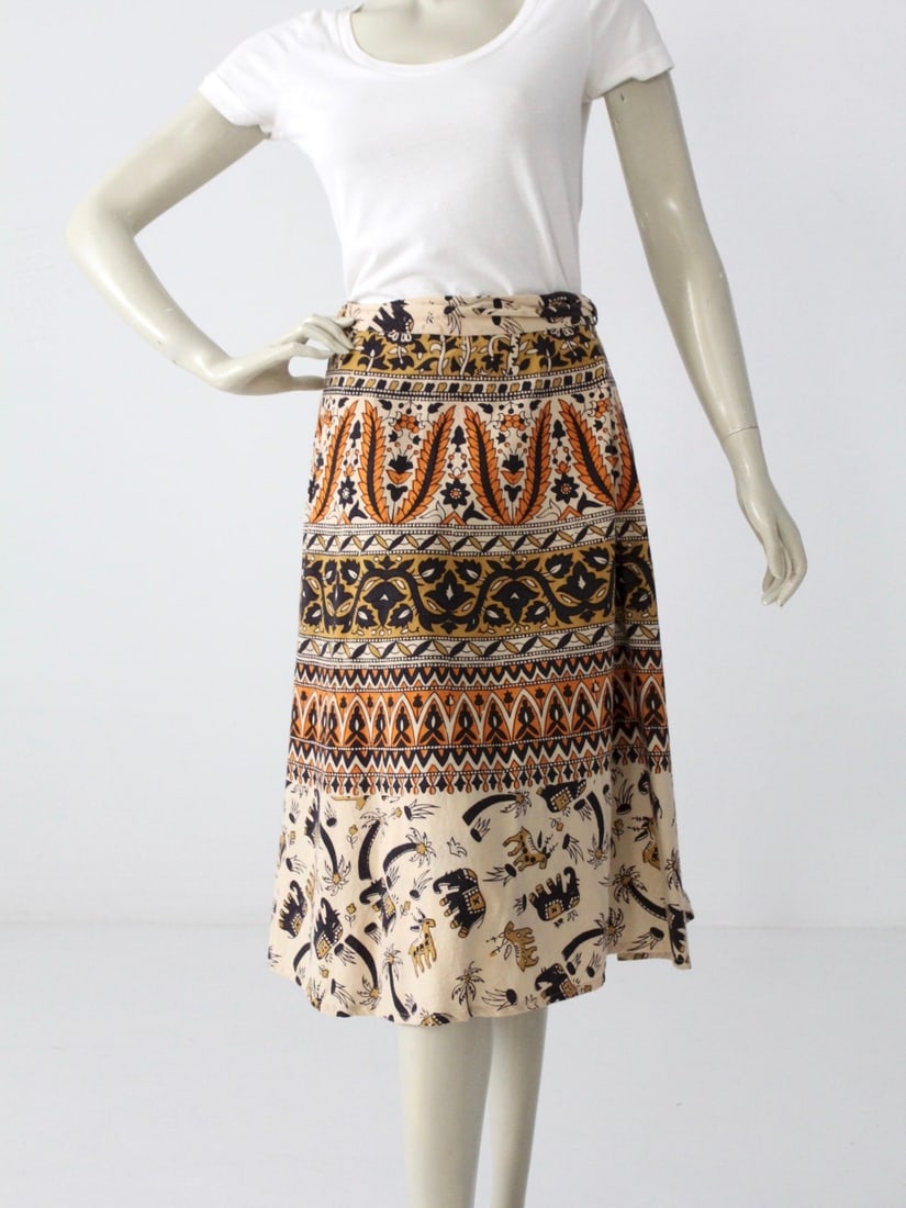 Vintage Boho Elephant Print Wrap Skirt in Cream Cotton: Vintage Boho Elephant Print Wrap Skirt in Cream Cotton This vintage boho wrap skirt features a whimsical design of elephants marching across a cream cotton fabric. It showcases a vibrant block print i
