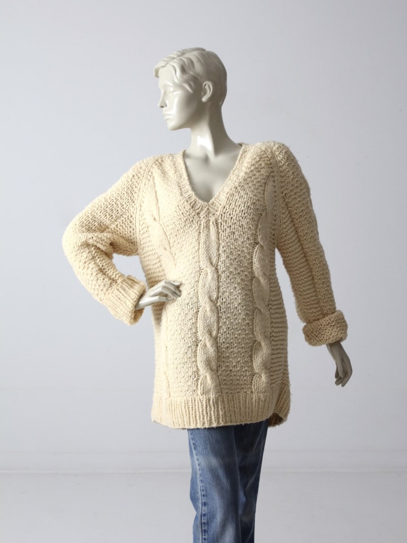 Vintage 80s Cream Chunky Knit Oversize V-Neck Sweater: Vintage 80s Cream Chunky Knit Oversize V-Neck Sweater Embrace retro fashion with this Vintage 80s Oversize V-Neck Sweater. This chunky knit piece features a stylish cream color and a distinctive cable