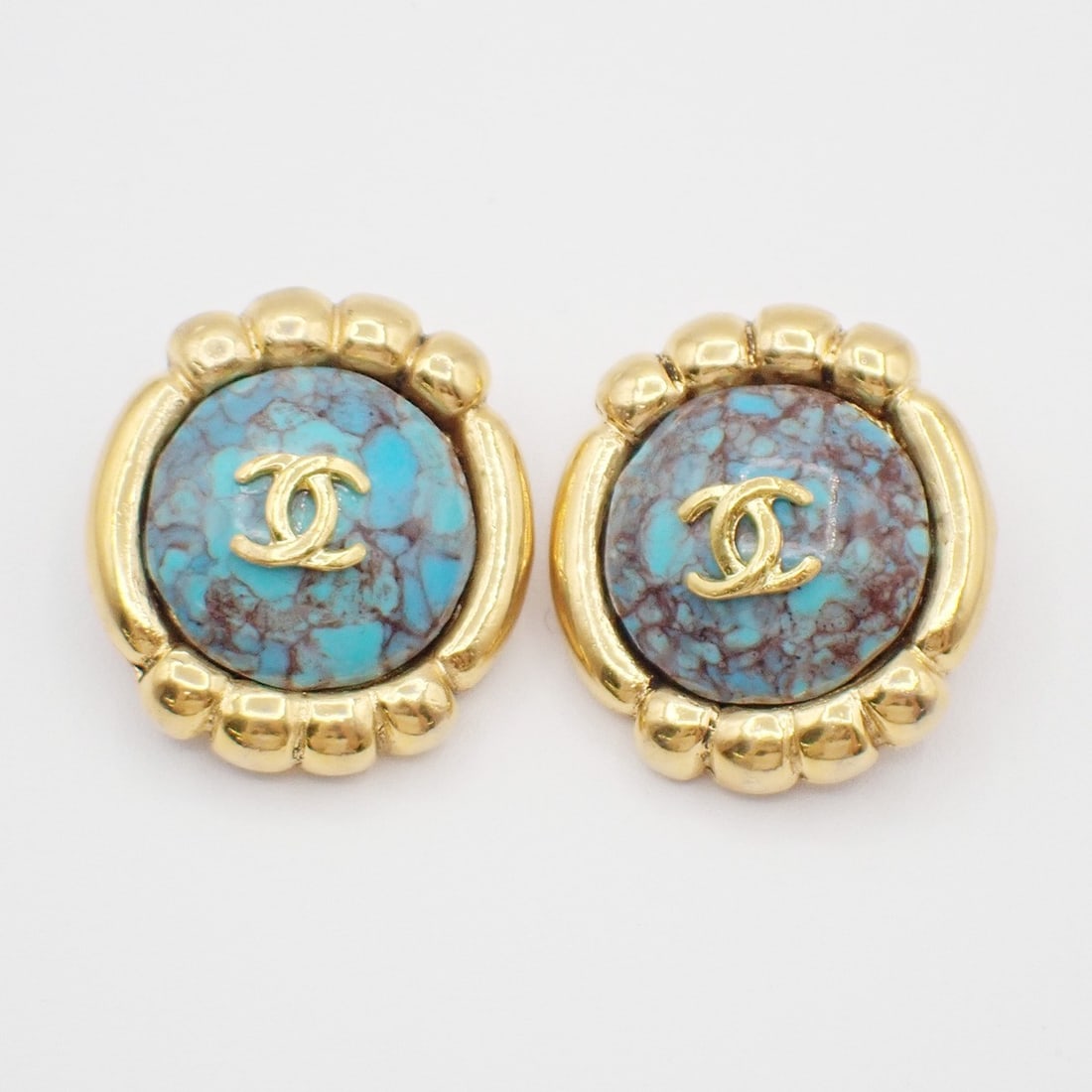 Vintage Round Clip-On Earrings with Blue CC Motif by Chanel: Vintage Round Clip-On Earrings with Blue CC Motif by Chanel These vintage Chanel round button clip-on earrings feature the iconic CC logo in blue. Designed for women, they display some noticeable scra