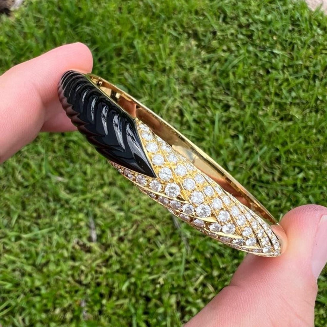 1980s 18K Yellow Gold Black Onyx Diamond Bangle Bracelet: 1980s 18K Yellow Gold Black Onyx Diamond Bangle Bracelet This stunning 1980's bangle bracelet features 18K yellow gold beautifully carved to showcase a striking black onyx centerpiece. It is adorned w