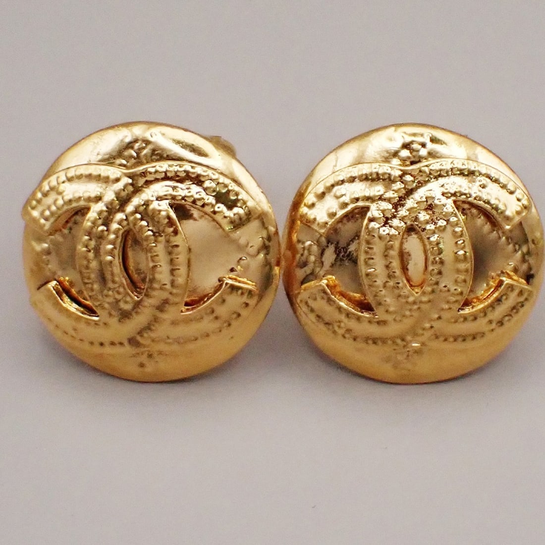Vintage Round Clip Earrings with CC Logo by Chanel Gold Tone: Vintage Round Clip Earrings with CC Logo by Chanel Gold Tone These vintage Chanel clip-on earrings feature the iconic CC logo in a round design. Crafted for women, they are presented in very good cond