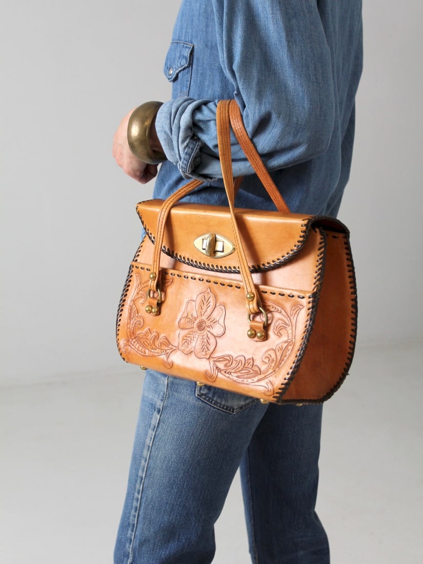 1960s Vintage Tooled Leather Handbag with Gold Tone Lock Clasp: 1960s Vintage Tooled Leather Handbag with Gold Tone Lock Clasp This stunning 1960s vintage tooled leather handbag showcases a beautiful caramel brown leather adorned with a delicate floral pattern. Th