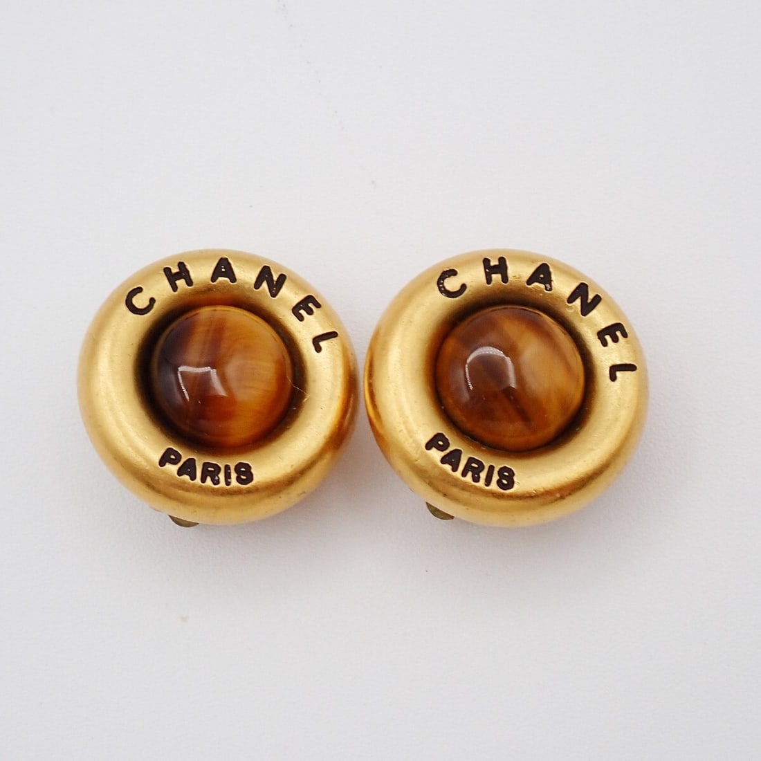 Vintage Gold-Tone Round CC Clip-On Earrings by Chanel: Vintage Gold-Tone Round CC Clip-On Earrings by Chanel These vintage Chanel round CC button clip-on earrings feature a gold tone finish and classic Chanel logo design. Suitable for female wearers, thes