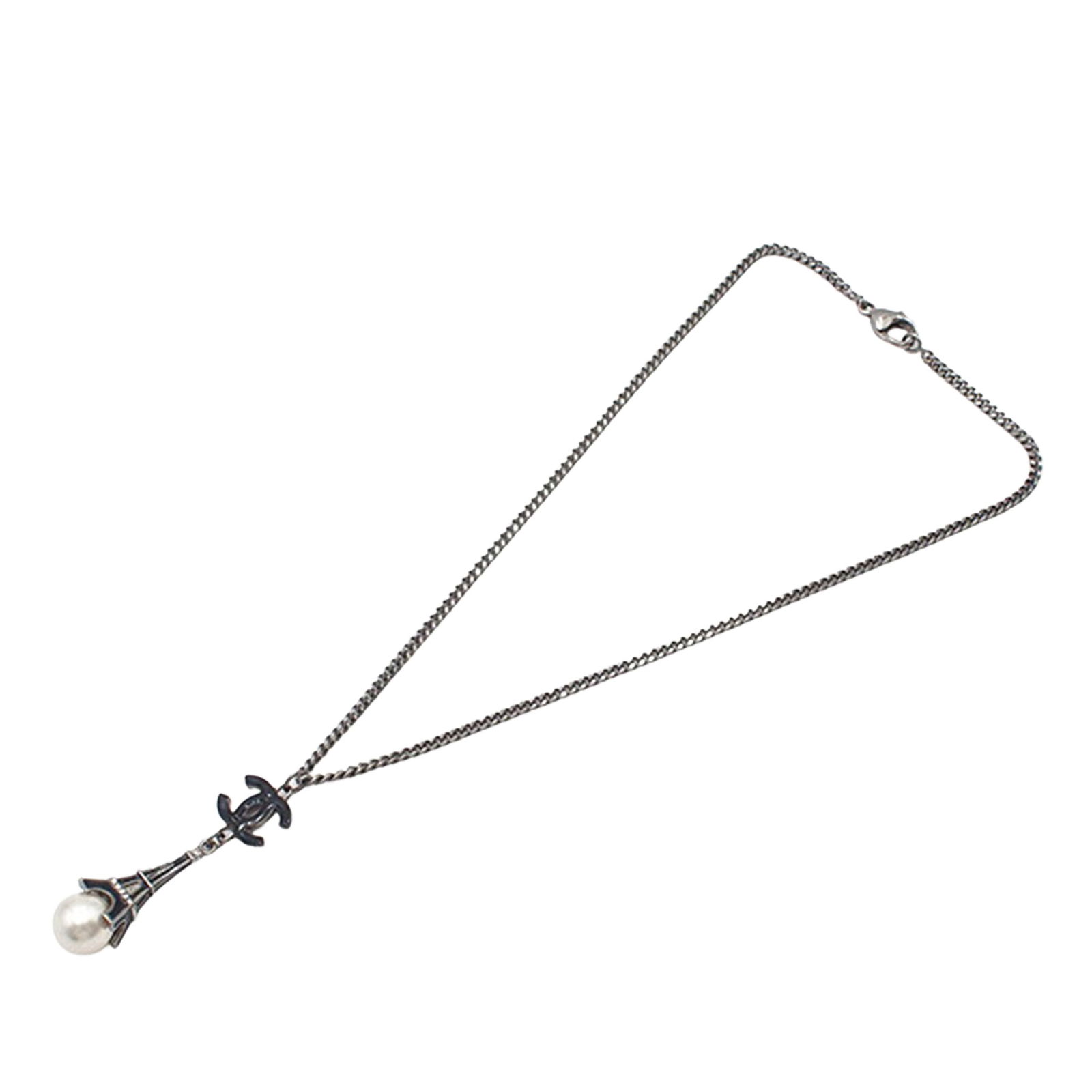 Chanel Silver Plated Faux Pearl CC Eiffel Tower Charm Necklace: Chanel Silver Plated Faux Pearl CC Eiffel Tower Charm Necklace Elevate your accessory collection with this exquisite Chanel necklace. Featuring a silver-tone chain adorned with a charming faux pearl a