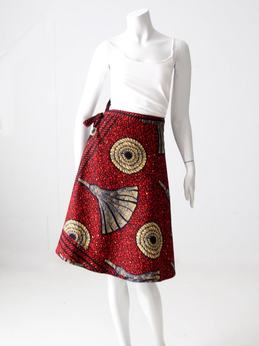 Vintage African Wrap Skirt Bold Floral Design Made in Nigeria: Vintage African Wrap Skirt Bold Floral Design Made in Nigeria This vintage African wrap skirt showcases a vibrant geometric floral design in bold red, blue, and yellow colors. It features long ties th