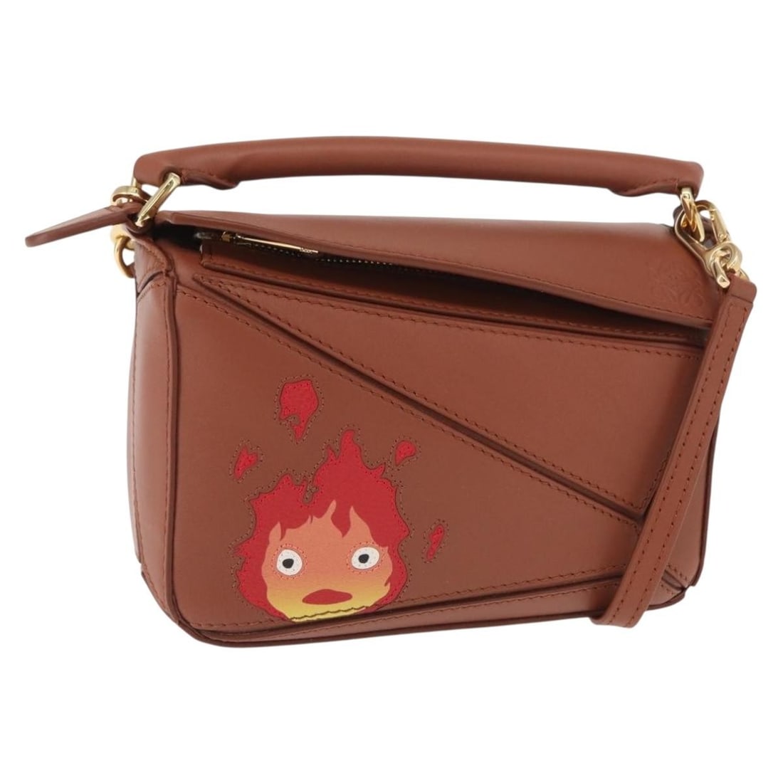 Brown Leather Mini Puzzle Handbag Loewe Studio Ghibli Calcifer Collaboration 2way: Brown Leather Mini Puzzle Handbag Loewe Studio Ghibli Calcifer Collaboration 2way This LOEWE Mini Puzzle Loewe x Studio Ghibli Calcifer bag is a two-way handbag crafted from brown leather with gold ac