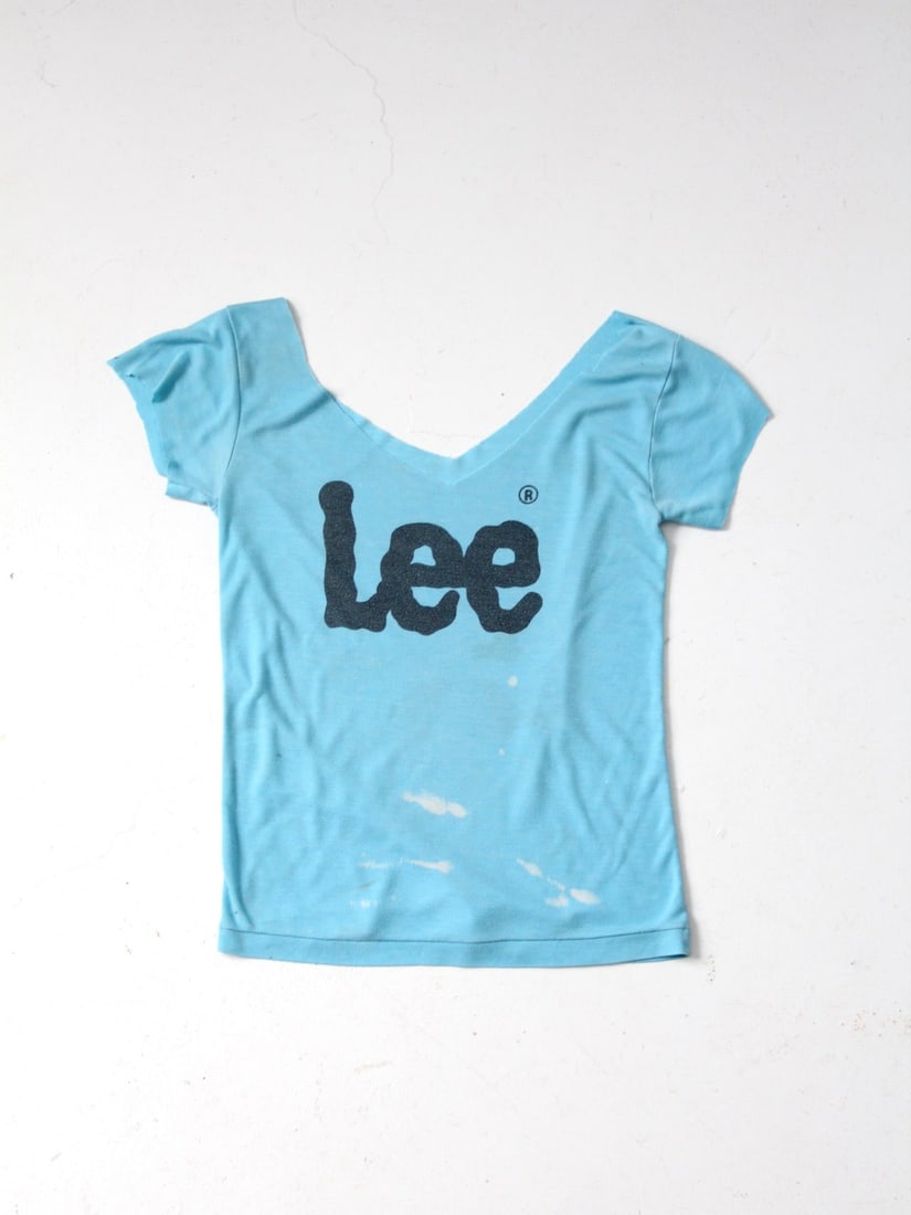 1980s Vintage Lee Sky Blue T-Shirt with V-Neck: 1980s Vintage Lee Sky Blue T-Shirt with V-Neck Embrace a piece of the past with this vintage 1980s Lee t-shirt. Crafted from ultra-soft fabric, this sky blue tee features a stylish wide v-neck and cro