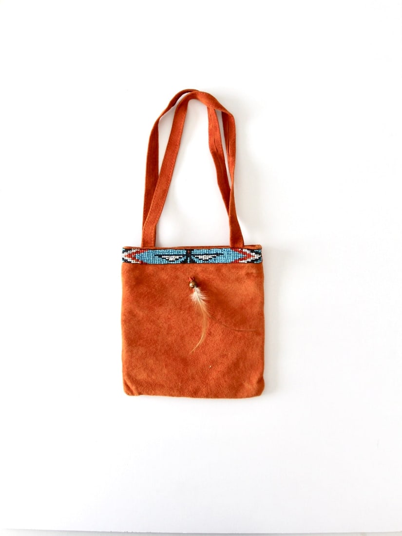 Vintage Orange Suede Boho Handbag with Beaded Feather: Vintage Orange Suede Boho Handbag with Beaded Feather Embrace a touch of vintage charm with this Boho-inspired suede handbag. Crafted from vibrant orange suede, this chic tote is adorned with intricat