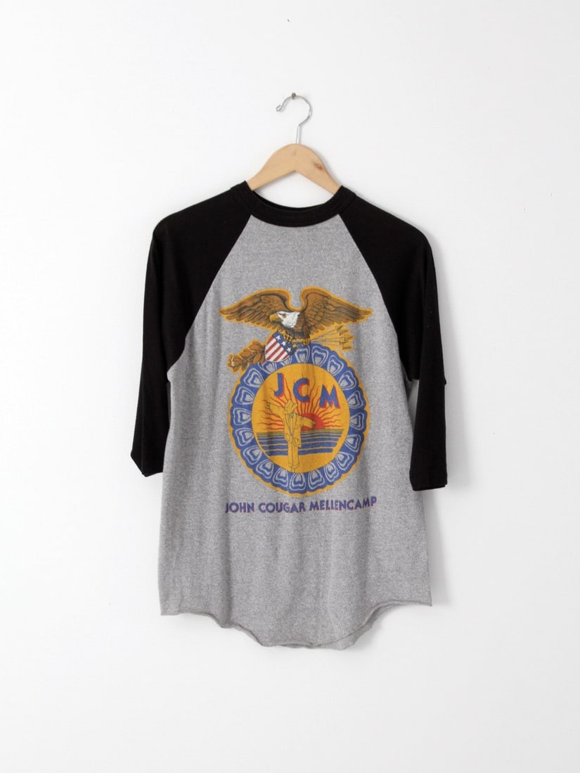 1986 Vintage John Cougar Mellencamp Scarecrow Tour T-Shirt: 1986 Vintage John Cougar Mellencamp Scarecrow Tour T-Shirt Celebrate the legacy of rock music with this vintage John Cougar Mellencamp t-shirt from the iconic 1986 Scarecrow tour. This stylish gray an