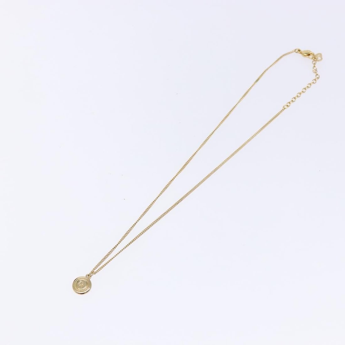 Round Pendant Necklace with Vintage Christian Dior Logo in Gold Tone: Round Pendant Necklace with Vintage Christian Dior Logo in Gold Tone This Christian Dior vintage round pendant necklace features the iconic logo design and a gold finish. The necklace shows slight sur