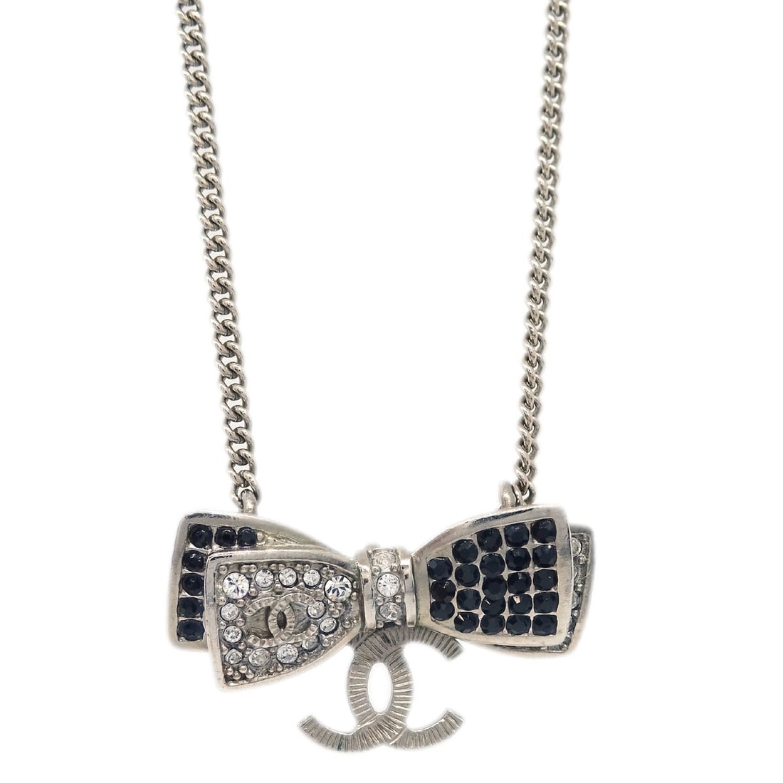 Chanel Silver Plated Bow Pendant Necklace with Rhinestones: Chanel Silver Plated Bow Pendant Necklace with Rhinestones Elevate your accessory collection with this exquisite Chanel Pendant Necklace featuring a charming bow shape. Crafted from silver-plated mate