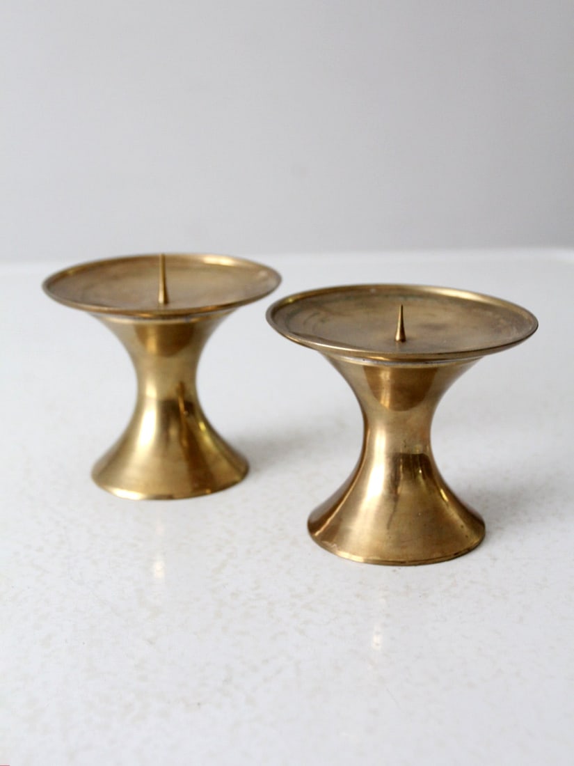 Elegant Vintage Brass Candle Pillar Pair Hourglass Design: Elegant Vintage Brass Candle Pillar Pair Hourglass Design Enhance your decor with this elegant pair of vintage brass candle pillars. Featuring hourglass-shaped pedestals, each pillar includes a lipped