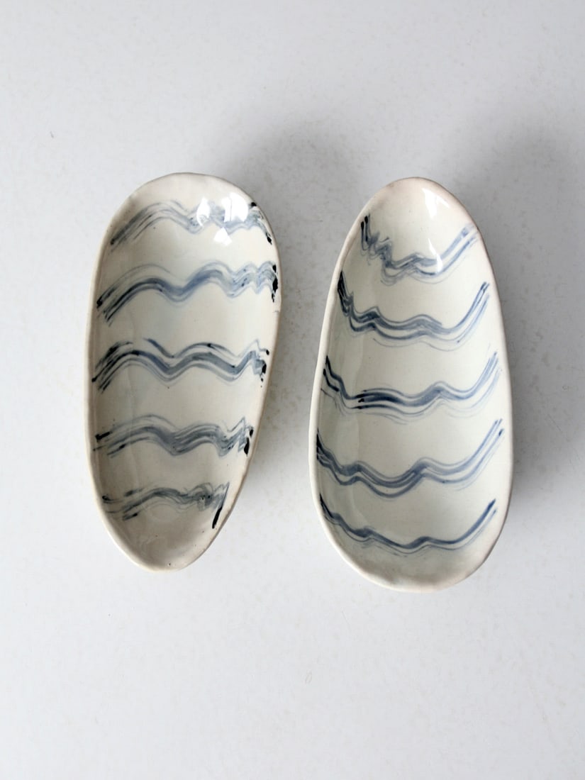 Handmade Vintage Studio Pottery Bowls Pair with Blue Waves: Handmade Vintage Studio Pottery Bowls Pair with Blue Waves This charming pair of vintage studio pottery bowls showcases a unique handmade design. Crafted with a glossy white finish, each oblong bowl f