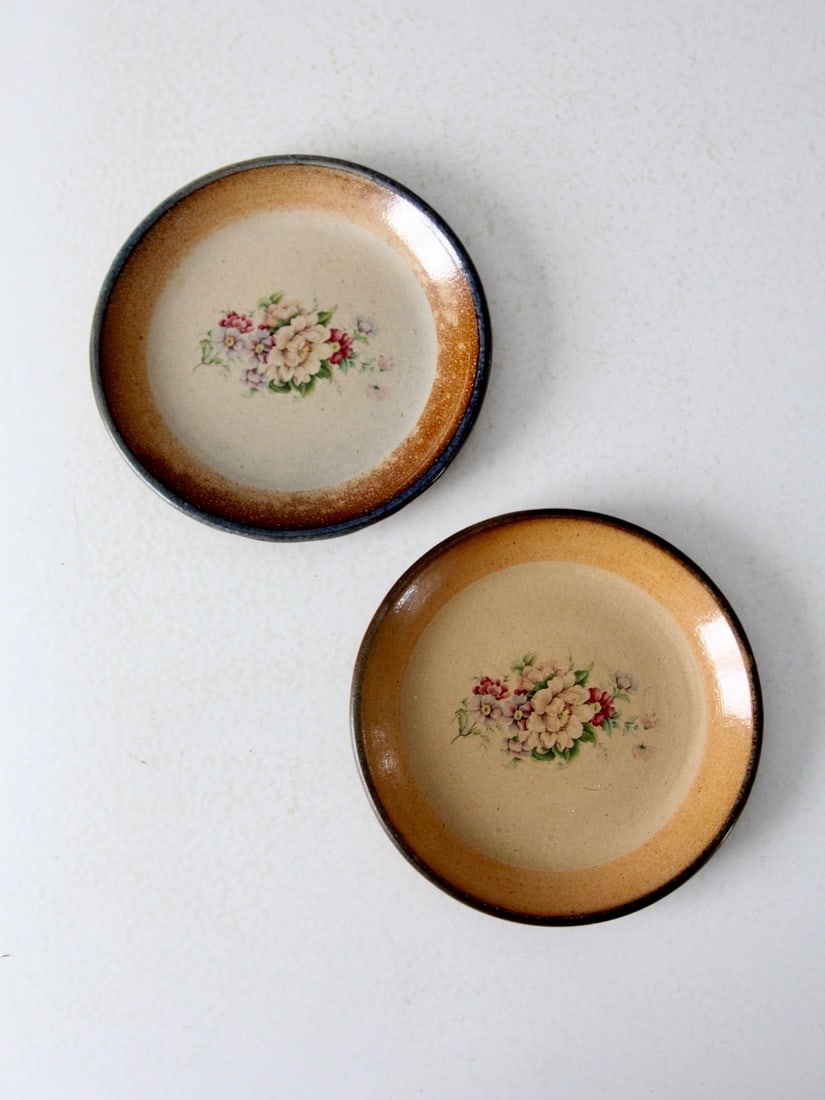 Charming Vintage Floral Pottery Plates Pair 8.75 Inch: Charming Vintage Floral Pottery Plates Pair 8.75 Inch This charming pair of vintage hand-crafted pottery plates showcases a delicate floral pattern in soft shades of pink, purple, and green. Each lunc