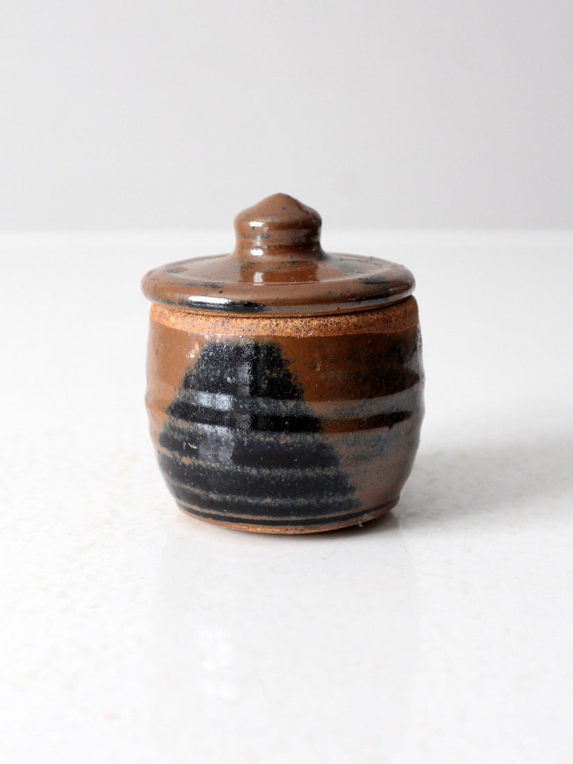 Signed Vintage Pottery Jar with Ribbed Design and Lid: Signed Vintage Pottery Jar with Ribbed Design and Lid This vintage studio pottery jar showcases a unique ribbed design, beautifully finished with a rich brown glaze complemented by bold black abstract