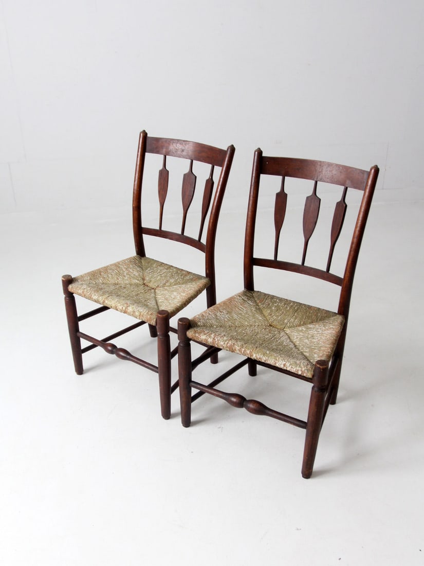 Antique Pair of Rush Seat Spindle Back Dining Chairs: Antique Pair of Rush Seat Spindle Back Dining Chairs This pair of antique spindle back dining chairs features elegant arrow back spindles complemented by turned stretchers and finials. The rush woven