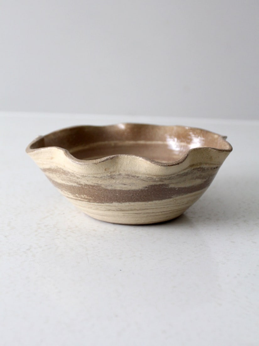 Signed Vintage Handmade Studio Pottery Bowl with Wavy Rim: Signed Vintage Handmade Studio Pottery Bowl with Wavy Rim Enhance your table setting with this vintage handmade studio pottery bowl. Featuring a wavy rim and a warm, earthy glaze, it brings character