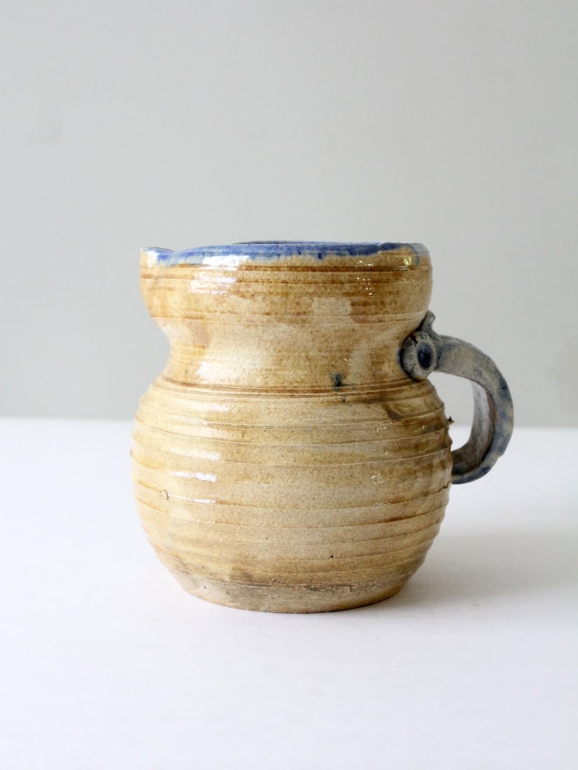 Handmade Vintage Studio Pottery Ewer with Tan Blue Glaze: Handmade Vintage Studio Pottery Ewer with Tan Blue Glaze This vintage studio pottery pitcher showcases a unique, robust design with a tan and light blue glaze. It features a rustic handle and a lipped