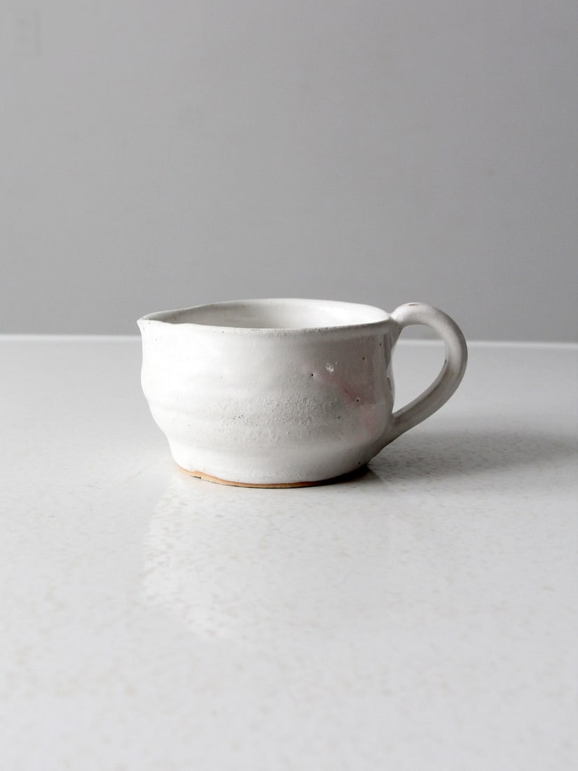 Charming Vintage Studio Pottery Pitcher with White Glaze: Charming Vintage Studio Pottery Pitcher with White Glaze This vintage studio pottery pitcher is a charming addition to your tableware collection. With its low height and bowl shape, it is ideal for se