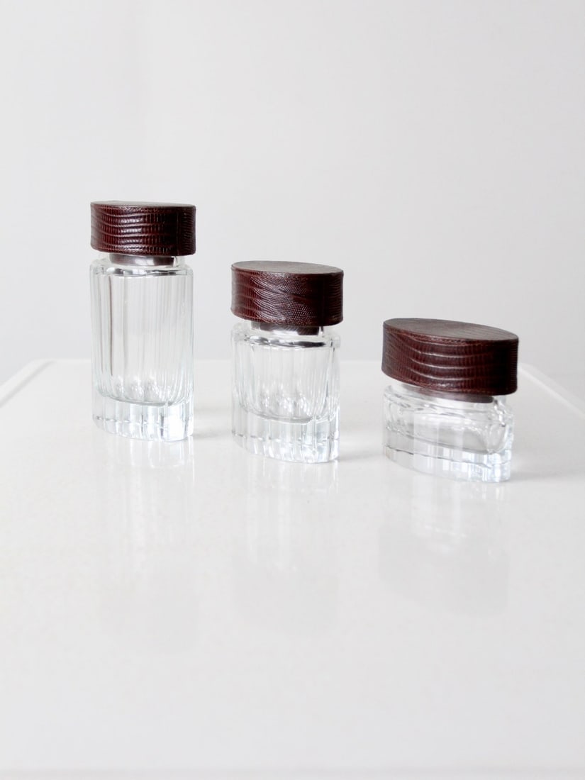 Set of 3 Vintage Glass Jars with Leather Lids: Set of 3 Vintage Glass Jars with Leather Lids Enhance your home decor with this charming set of three vintage cut glass jars featuring elegant leather lids. Each jar showcases a unique graduated size