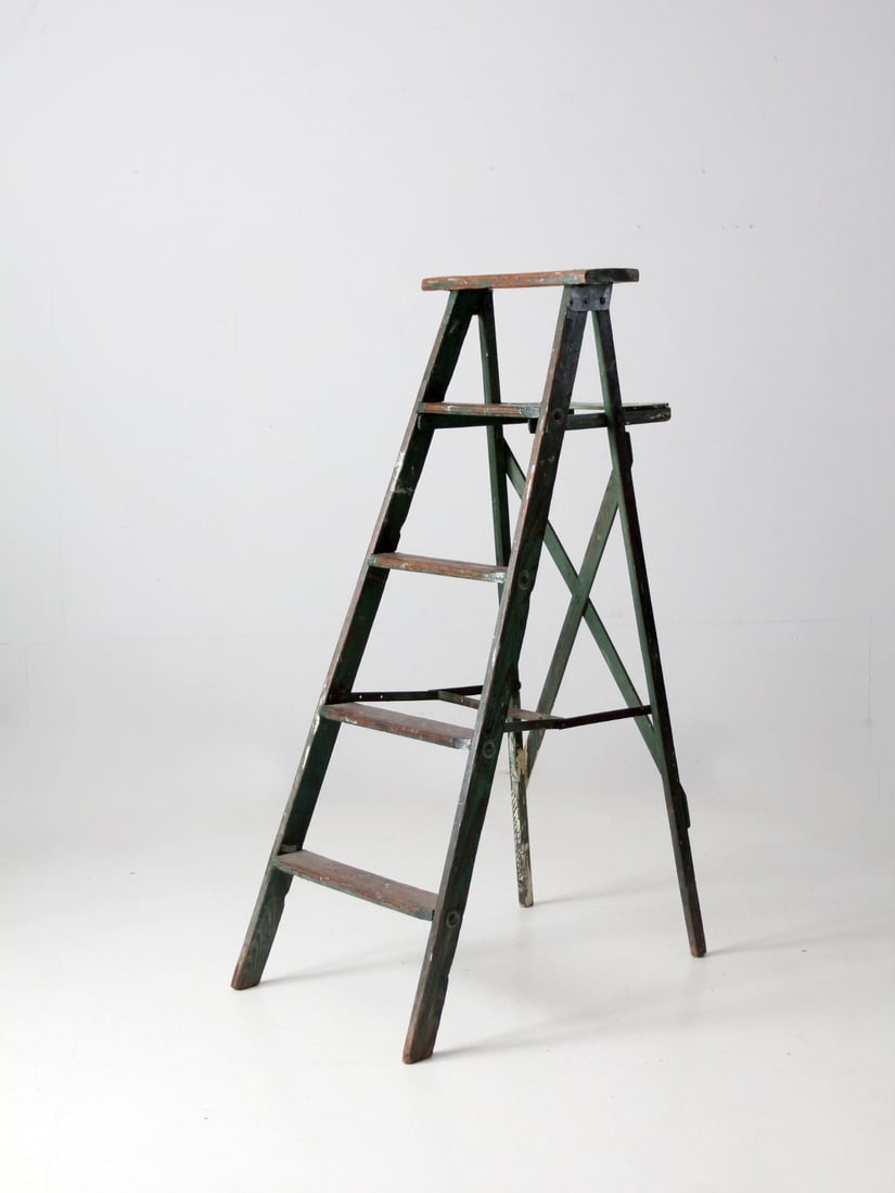 Vintage Green A-Frame Wooden Ladder with Shelf 54 Inch: Vintage Green A-Frame Wooden Ladder with Shelf 54 Inch This vintage green wooden ladder showcases a charming a-frame design with four sturdy rung steps, a back shelf, and crossing back braces. Its ric