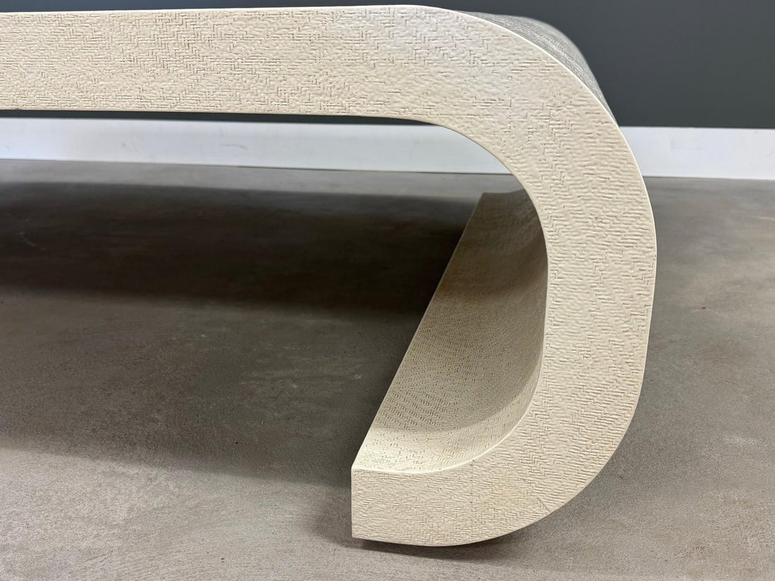 1980s Karl Springer Inspired White Grass Cloth Coffee Table: 1980s Karl Springer Inspired White Grass Cloth Coffee Table This stunning post-modern coffee table showcases a white grass cloth finish and features elegant scroll sides, reflecting the iconic style o