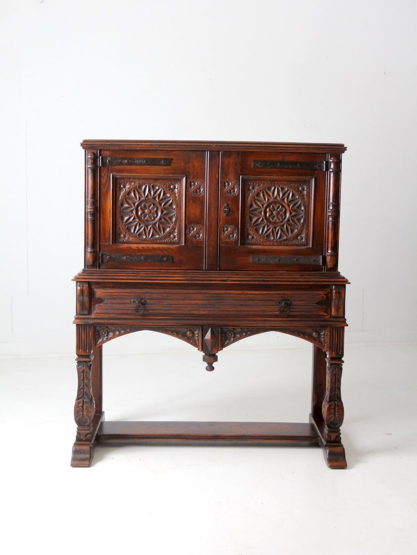 Antique Gothic Cabinet with Floral Carvings and Iron Pulls: Antique Gothic Cabinet with Floral Carvings and Iron Pulls This stunning antique Gothic style cabinet showcases exquisite floral carvings on both its doors and frame, adding a touch of elegance to any