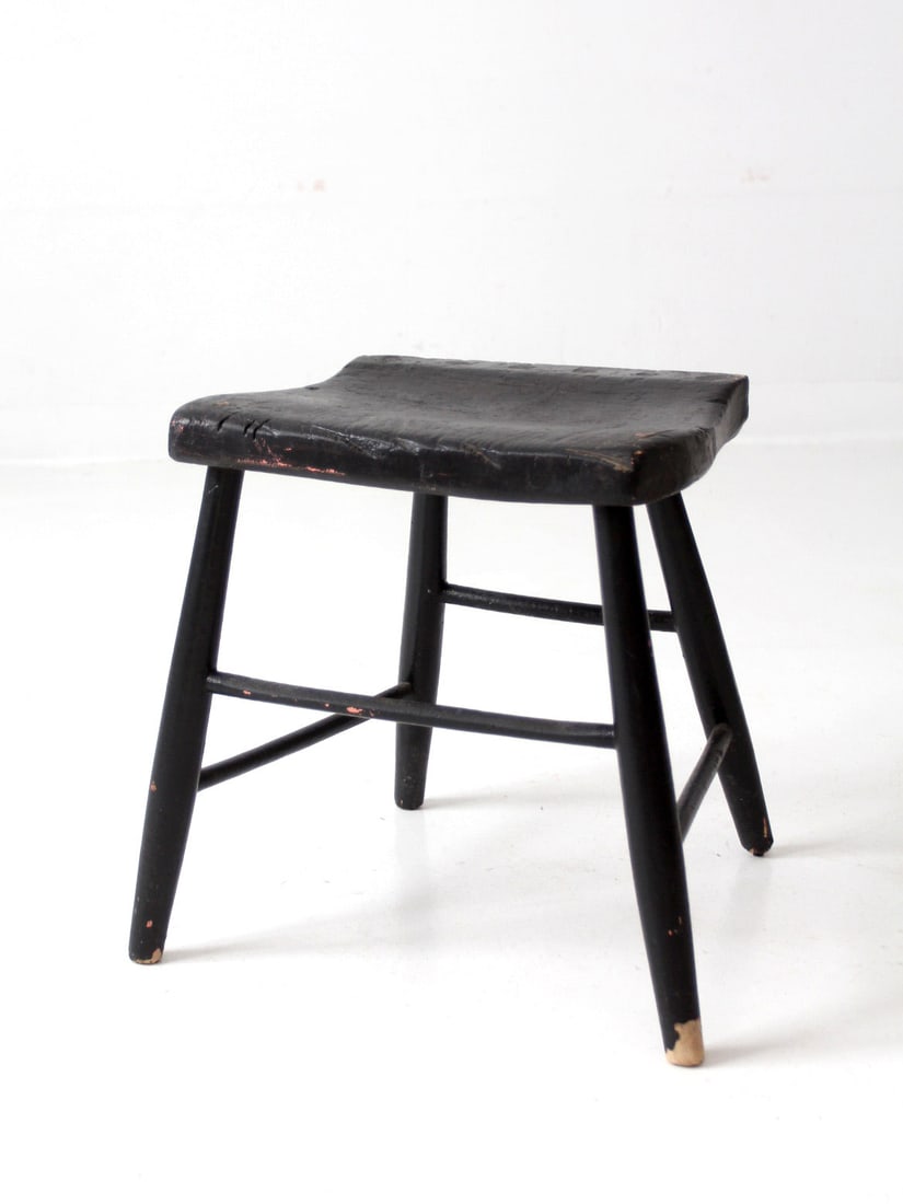 Rustic Antique Black Wooden Stool with Windsor Seat: Rustic Antique Black Wooden Stool with Windsor Seat This antique wooden stool features a charming aged black paint finish, showcasing its rustic character. The seat is shaped like a Windsor chair and