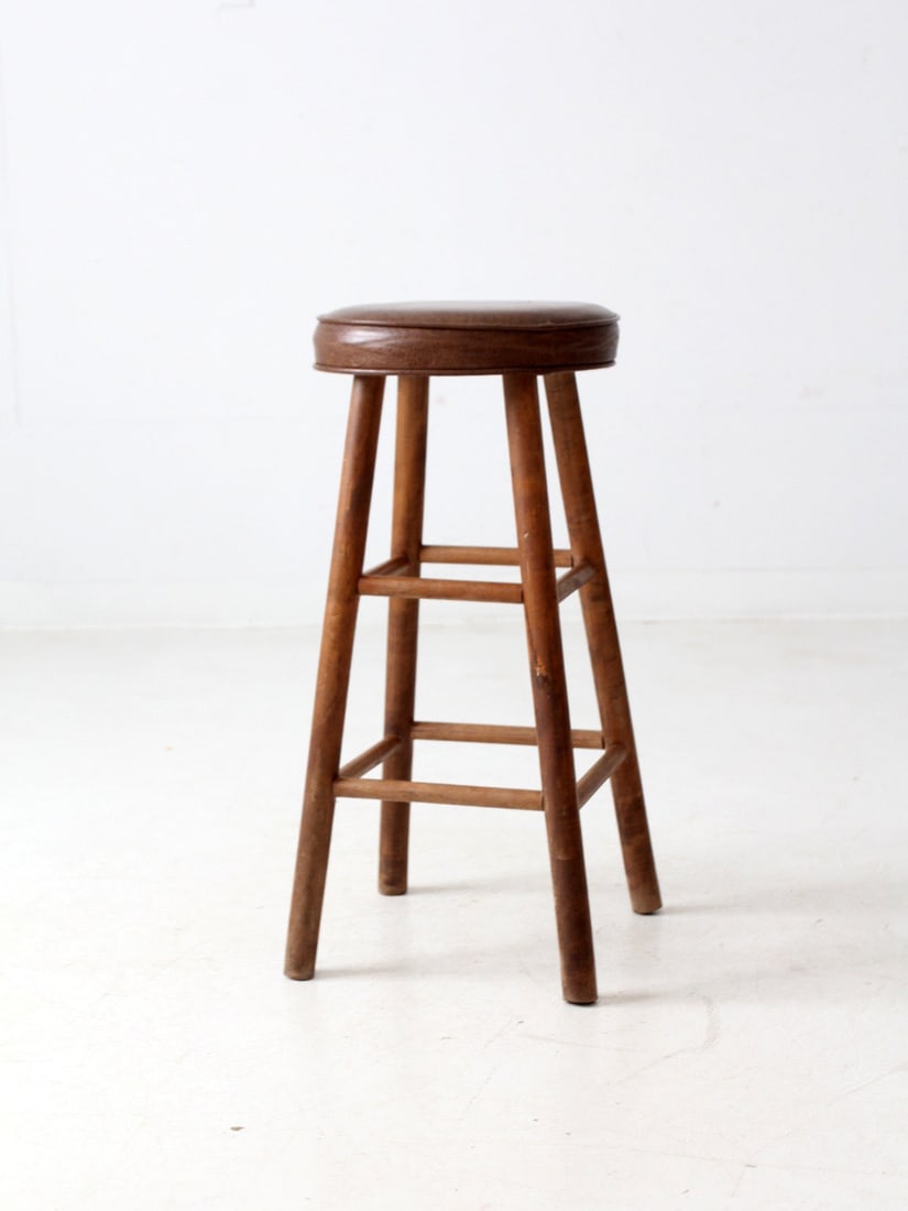 Classic Vintage Wooden Bar Stool with Faux Leather Seat: Classic Vintage Wooden Bar Stool with Faux Leather Seat This vintage wooden bar stool combines a classic design with modern comfort. It features a sturdy wooden frame accented by a warm brown faux lea
