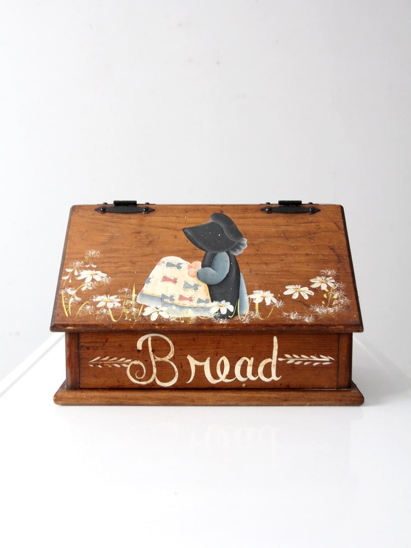 Vintage Hand-Painted Folk Art Wood Bread Box with Holly Hobbie Design: Vintage Hand-Painted Folk Art Wood Bread Box with Holly Hobbie Design This vintage hand-painted wood bread box features a charming sloped lid and a warm wood tone. Adorned with a Holly Hobbie style fo