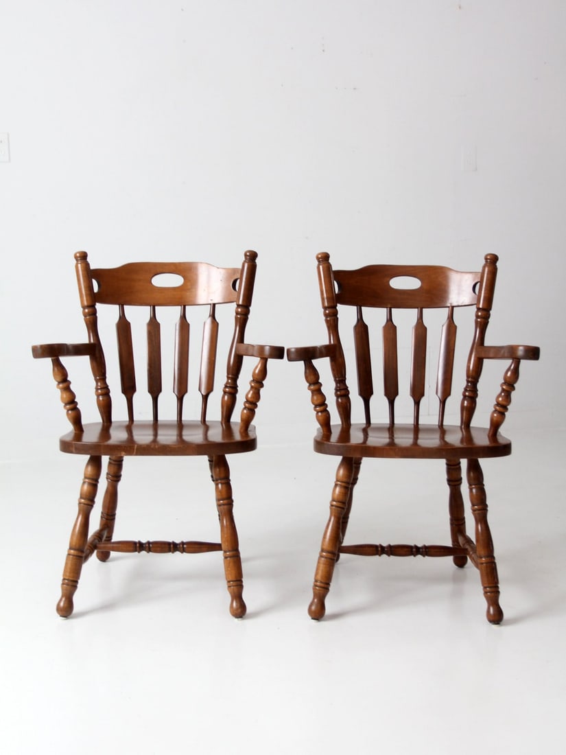 Vintage Mid Century Captain's Chairs Pair from Yugoslavia: Vintage Mid Century Captain's Chairs Pair from Yugoslavia This pair of mid 20th century vintage captain's chairs showcases a classic design with wooden armrests, saddle seats, cattail spindle backs, a
