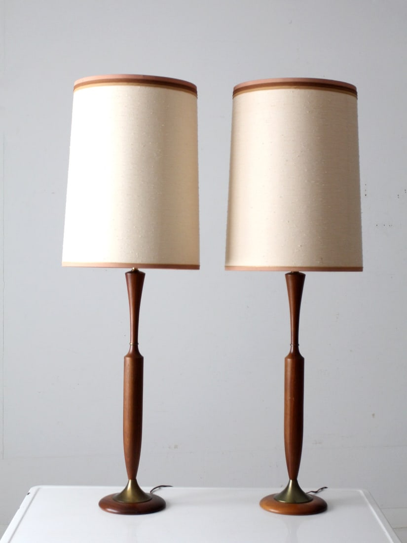 Mid Century Pair of Teak Table Lamps with Brass Accents: Mid Century Pair of Teak Table Lamps with Brass Accents This exquisite pair of mid-century table lamps showcases elegant, slender, tapered teak stems that exude warmth and sophistication. Each lamp is