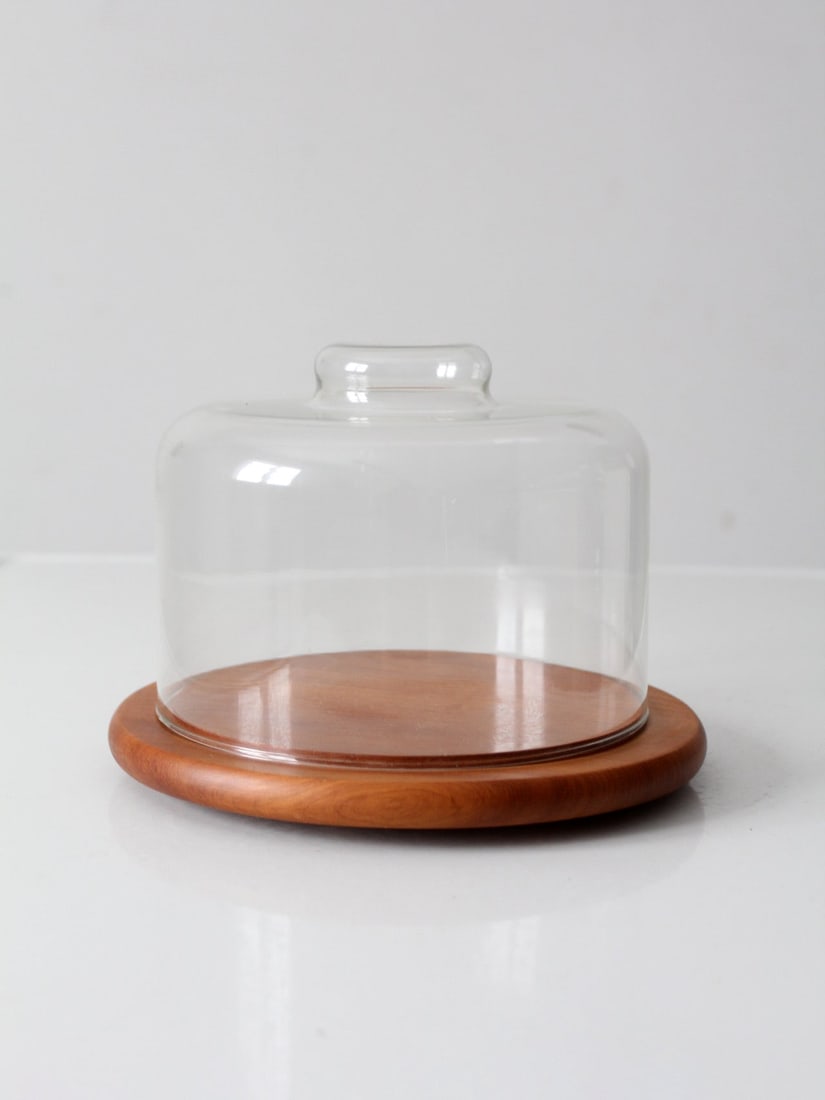 Dolphin Mid-Century Teak Cheese Board with Glass Dome: Dolphin Mid-Century Teak Cheese Board with Glass Dome This exquisite mid-century teak cheese board features a glass dome crafted by Dolphin. The round teak base showcases a warm golden hue and a reces