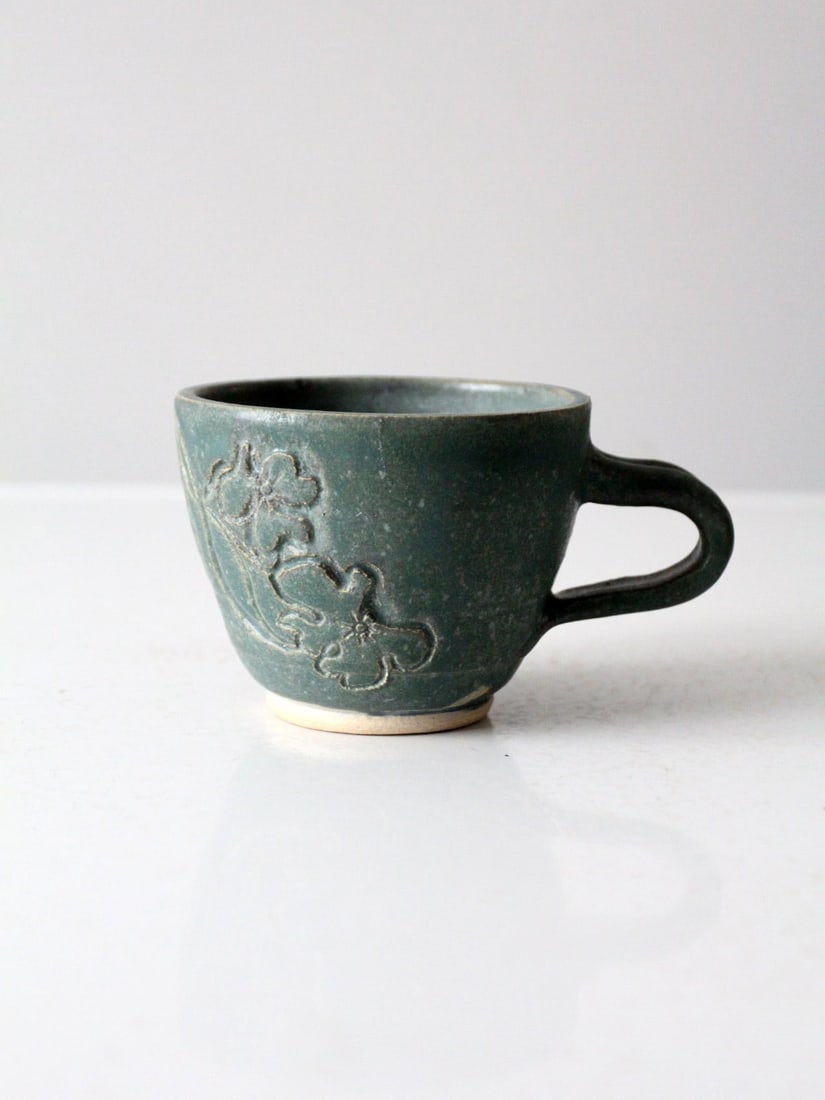 Signed Vintage Studio Pottery Mug with Floral Design: Signed Vintage Studio Pottery Mug with Floral Design This vintage handmade studio pottery mug showcases a beautifully etched floral design complemented by a rich teal-green glaze. A perfect addition t