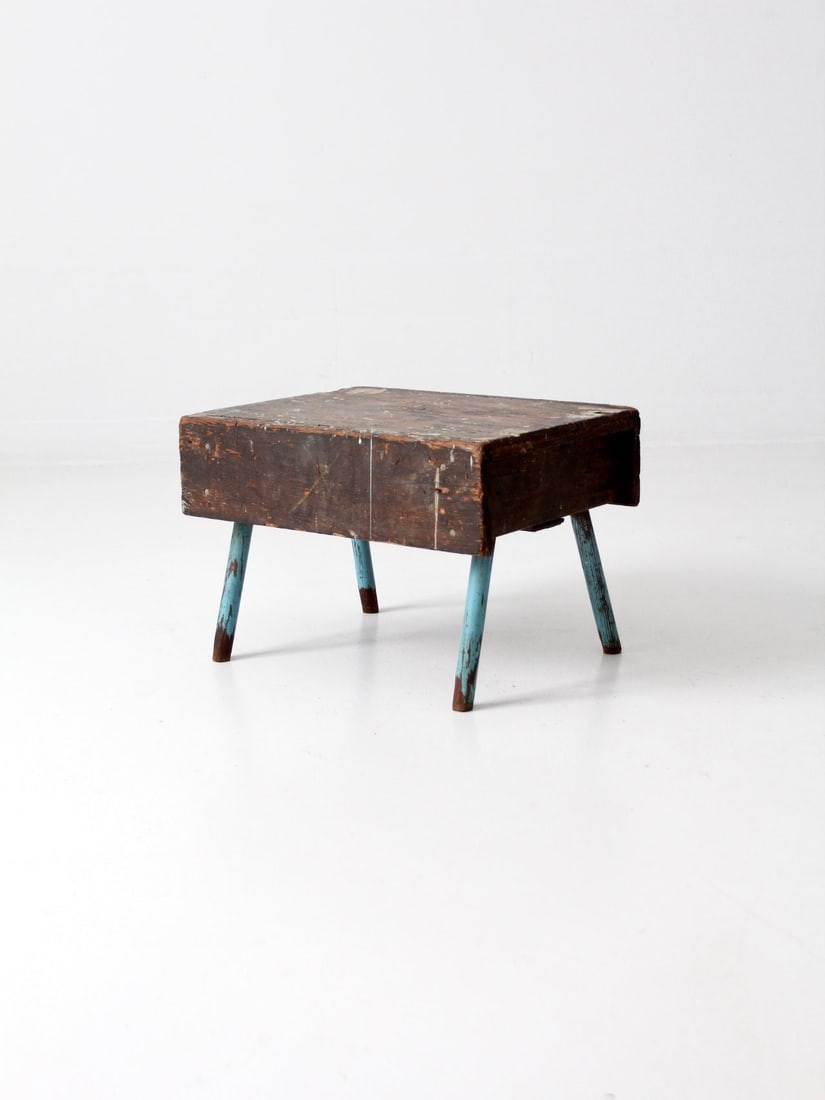 Rustic Vintage Wooden Stool with Blue Splayed Legs: Rustic Vintage Wooden Stool with Blue Splayed Legs This rustic vintage stool showcases a charming hand-crafted design with distinctive blue splayed legs and a box-style top. Its natural wear and paint
