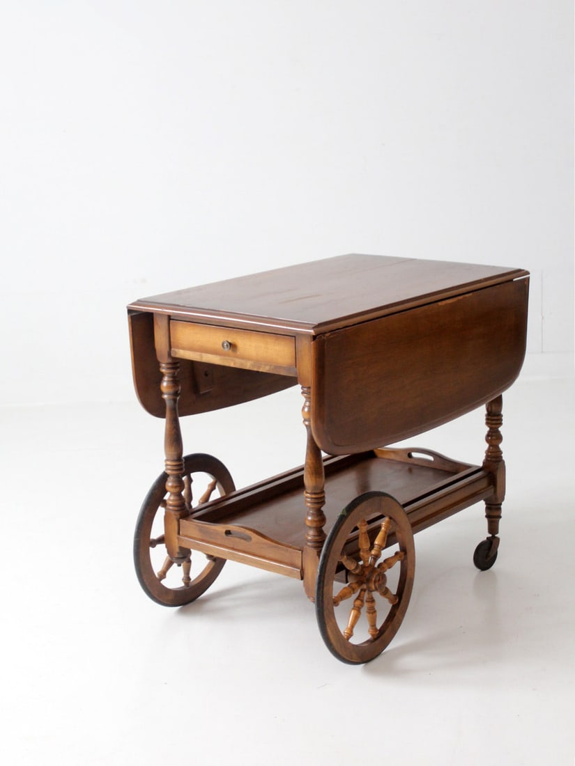 Mid Century Colonial Serving Cart with Drop Leaf and Tray: Mid Century Colonial Serving Cart with Drop Leaf and Tray This mid-century Colonial style tea or bar cart is a perfect blend of functionality and vintage charm. It features a drop leaf tabletop that e