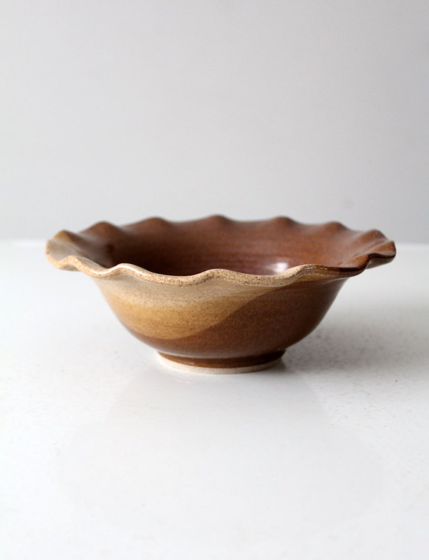 Vintage Handcrafted Ceramic Bowl with Ruffled Edge: Vintage Handcrafted Ceramic Bowl with Ruffled Edge This vintage handcrafted ceramic bowl showcases a stunning two-tone brown and tan glaze complemented by a charming ruffled edge. Perfect for serving