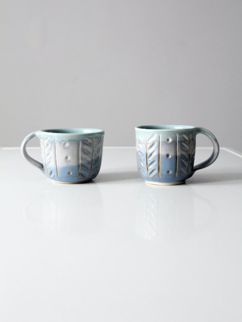 Handcrafted Vintage Studio Pottery Mugs Pair with Etched Design: Handcrafted Vintage Studio Pottery Mugs Pair with Etched Design This exquisite pair of vintage studio pottery mugs features a stunning three-tone glaze in shades of blue and gray, complemented by an i