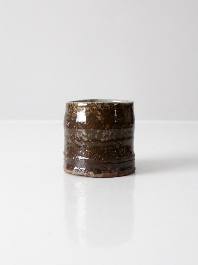 Handmade Vintage Studio Pottery Vase with Earthy Glaze: Handmade Vintage Studio Pottery Vase with Earthy Glaze This vintage handmade studio pottery vase features an earthy brown glaze, showcasing subtle shifts of olive and clay tones. Its compact shape and