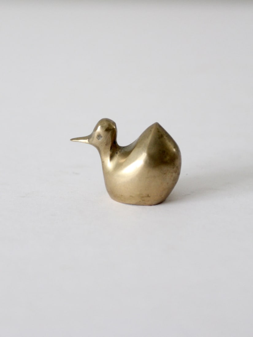 Charming Mid-Century Mini Brass Duck Figurine: Charming Mid-Century Mini Brass Duck Figurine This charming mid-century mini brass duck figurine features a playful design with modern, sleek lines. It is in good condition, showing wear consistent wi
