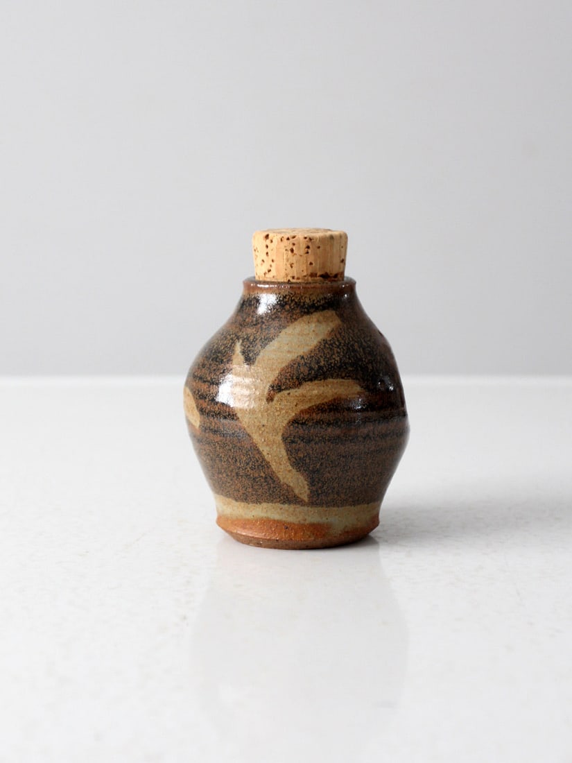 Signed Vintage Studio Pottery Jar with Cork Closure: Signed Vintage Studio Pottery Jar with Cork Closure This vintage studio pottery jar is a charming addition to any kitchen decor. Handcrafted by the artist, it features a warm brown and tan glaze with