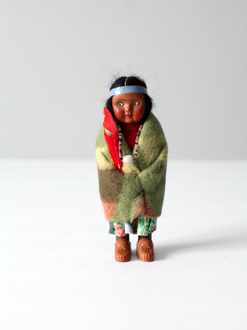 1950s Vintage Skookum Bully Good Indian Doll: 1950s Vintage Skookum Bully Good Indian Doll This charming 1950s vintage Skookum Bully Good Indian doll showcases a classic Native American design. Crafted with a plastic body, it features a wool blan