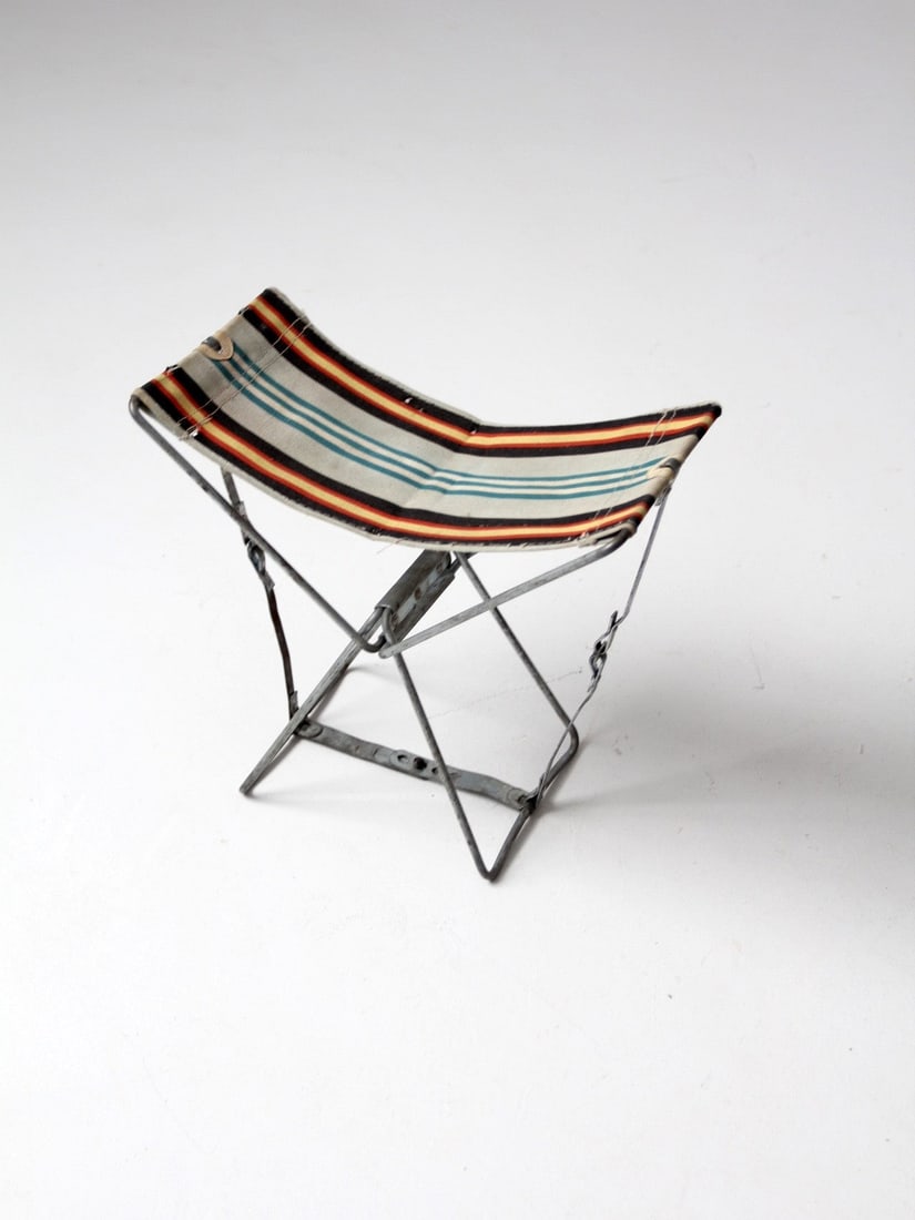 Vintage Folding Camp Stool with Adjustable Striped Canvas Seat: Vintage Folding Camp Stool with Adjustable Striped Canvas Seat Discover this vintage camping stool, perfect for outdoor enthusiasts. This compact folding stool features a sturdy metal frame and an adj