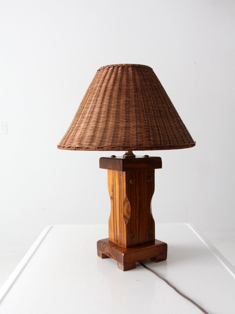 Mid 20th Century Vintage Wooden Table Lamp with Wicker Shade: Mid 20th Century Vintage Wooden Table Lamp with Wicker Shade This mid 20th century vintage lodge-style table lamp showcases a robust wooden base paired with a woven wicker shade, creating a timeless a