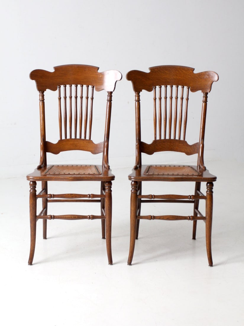 Antique Victorian Spindle Back Chairs Pair with Aged Leather Seats: Antique Victorian Spindle Back Chairs Pair with Aged Leather Seats This exquisite pair of Antique American Victorian spindle back chairs showcases beautiful craftsmanship with shaped crest rails, turn