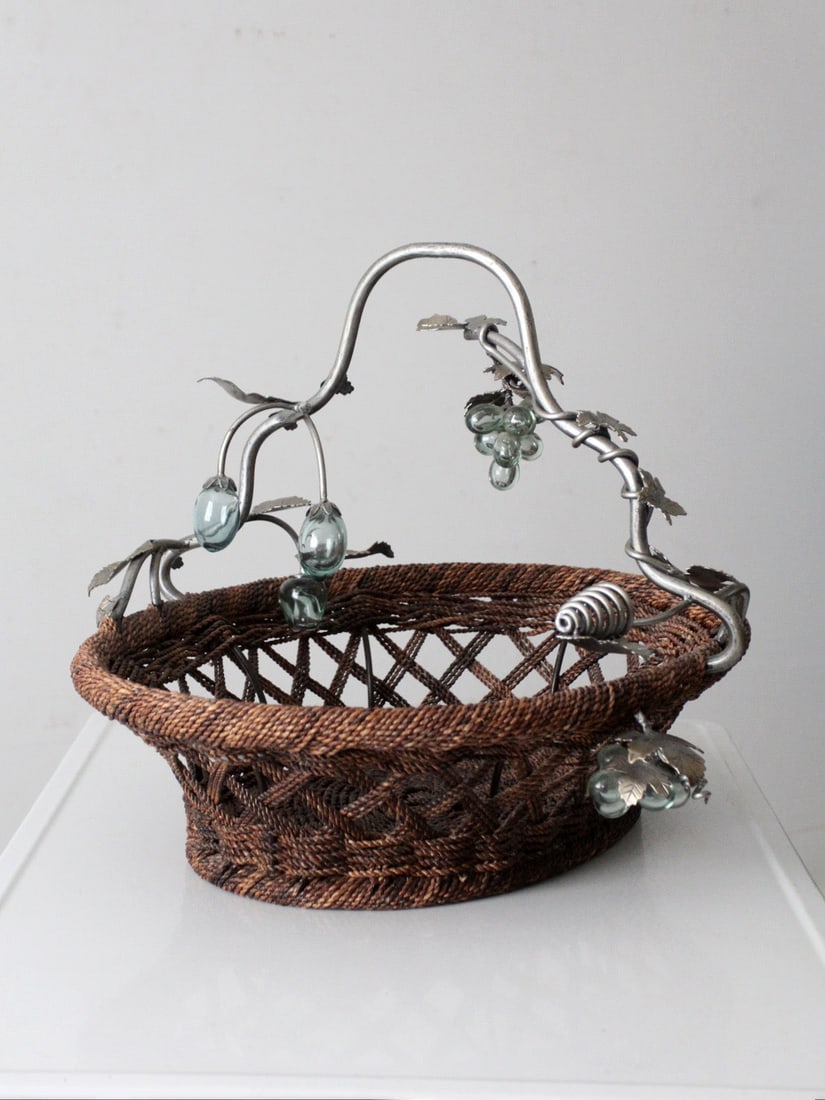 Sculptural Metal and Glass Grapevine Handle Basket with Woven Base 27in: Sculptural Metal and Glass Grapevine Handle Basket with Woven Base 27in This large vintage decorative basket features a woven base complemented by a sculptural metal grapevine handle with leaf accents