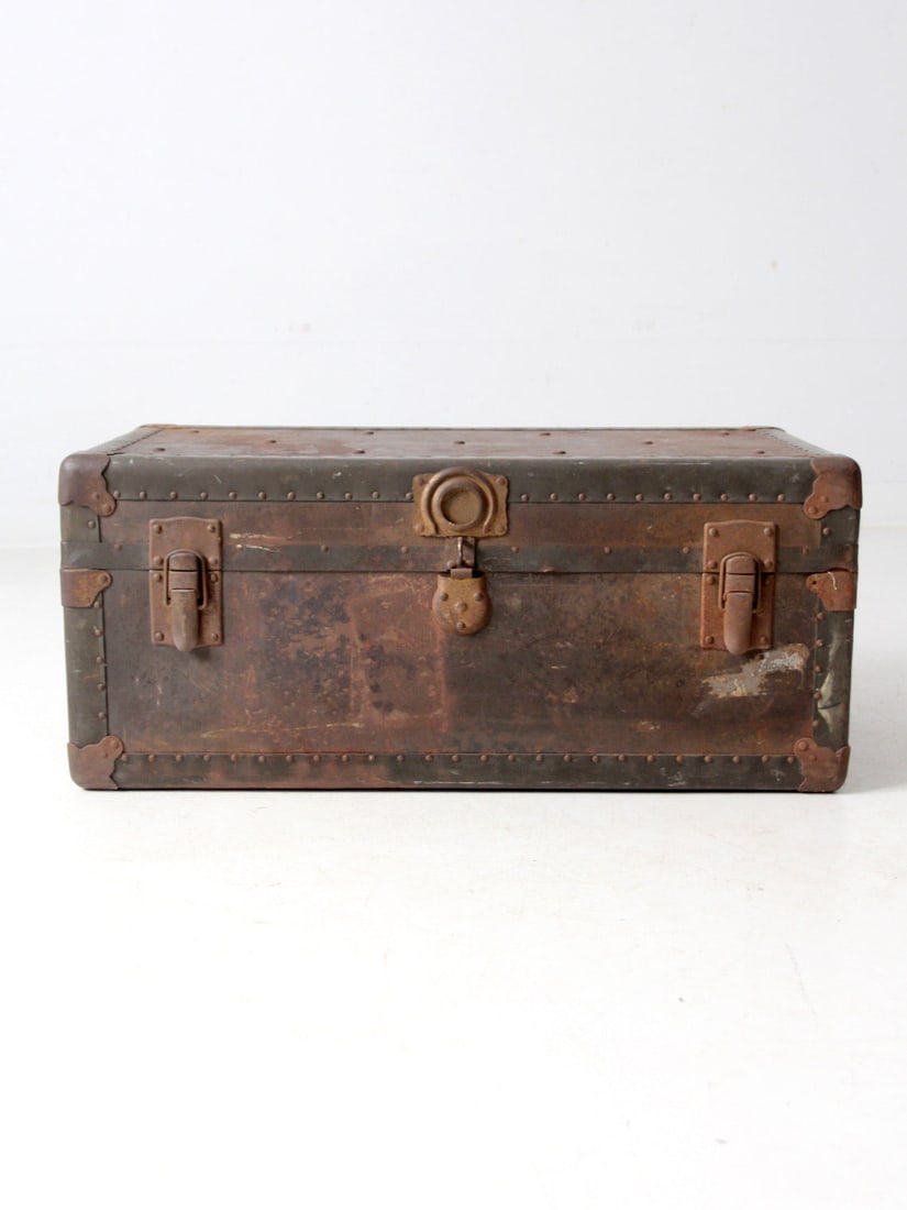 WWII Era Tronick-McKenzie Industrial Metal Trunk Locker: WWII Era Tronick-McKenzie Industrial Metal Trunk Locker This WWII-era metal trunk locker by Tronick-McKenzie Co. serves as a captivating decorative piece with its aged metal surface, reinforced corner