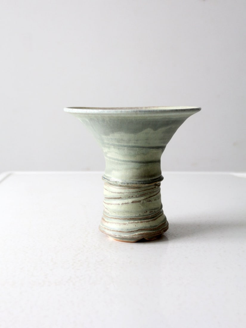 Signed Vintage Studio Pottery Vase Green Glaze 7.75in: Signed Vintage Studio Pottery Vase Green Glaze 7.75in This vintage studio pottery vase showcases a unique and bold design, expertly crafted by an artist. The vase features a soft green glaze accented
