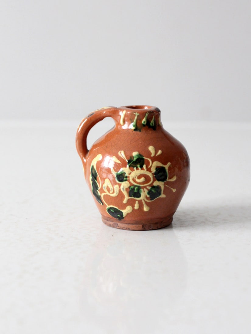 Vintage Eastern European Slipware Mini Jug with Floral Motifs: Vintage Eastern European Slipware Mini Jug with Floral Motifs This vintage Eastern European slipware mini jug showcases a beautiful reddish-brown glaze adorned with raised floral motifs in green and y